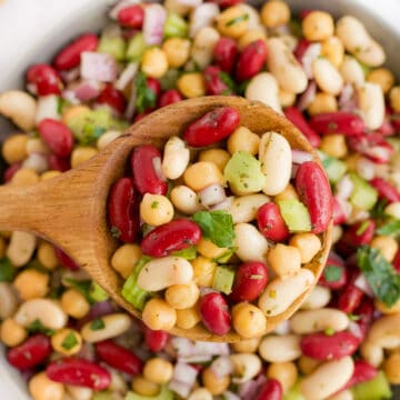 three bean salad being scooped by a wooden spoon