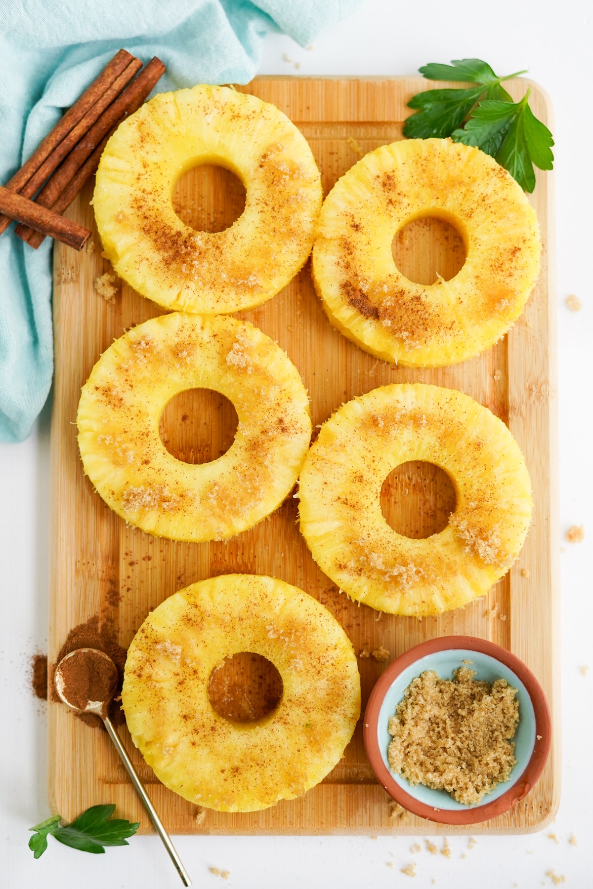 5 pineapple rings dusted with cinnamon on a wooden board