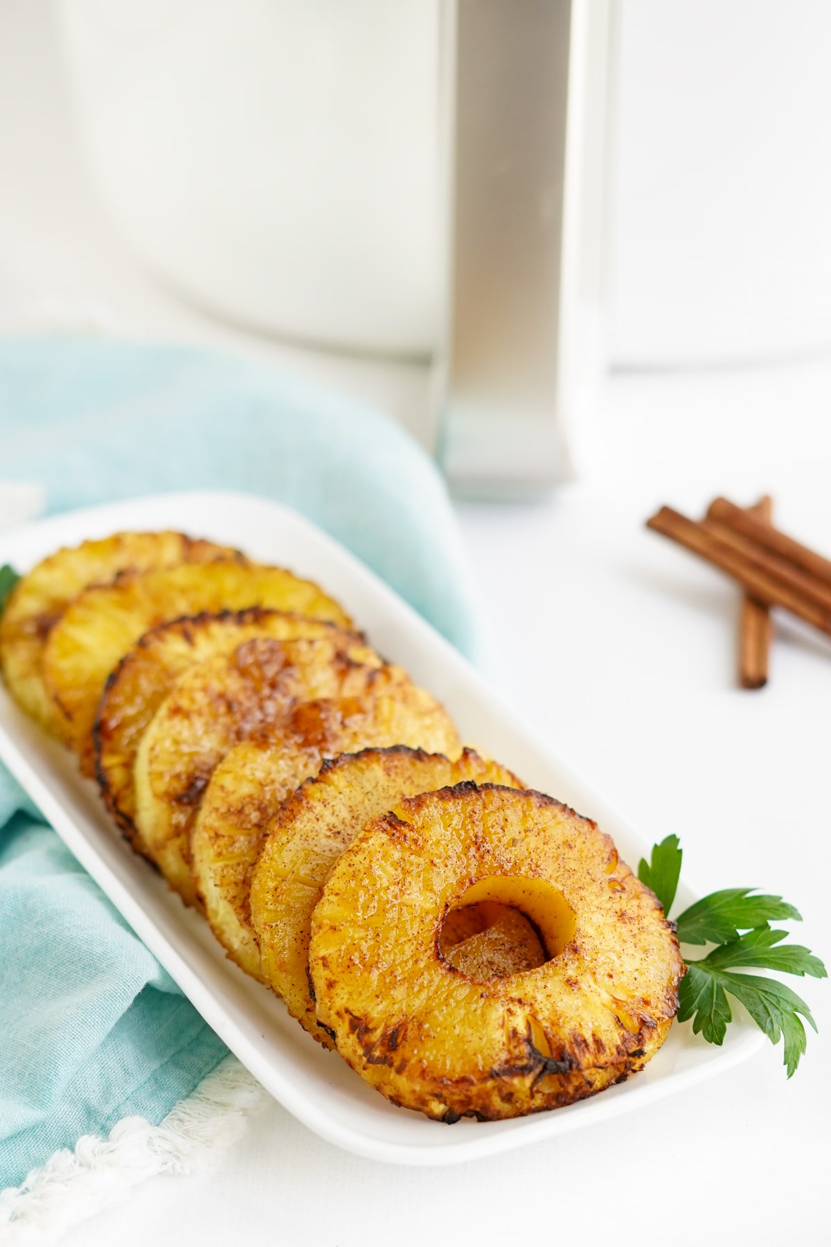 air fryer pineapple on a white platter with parsley garnish