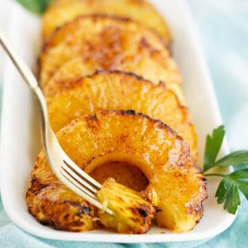 caramelized pineapple rings on white platter with fork