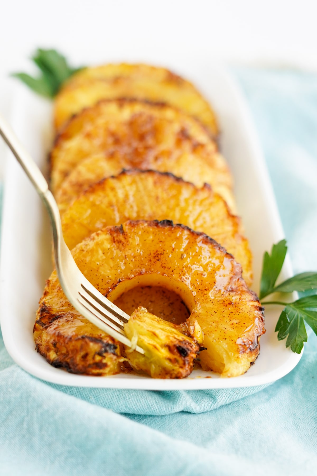 caramelized pineapple rings on white platter with fork