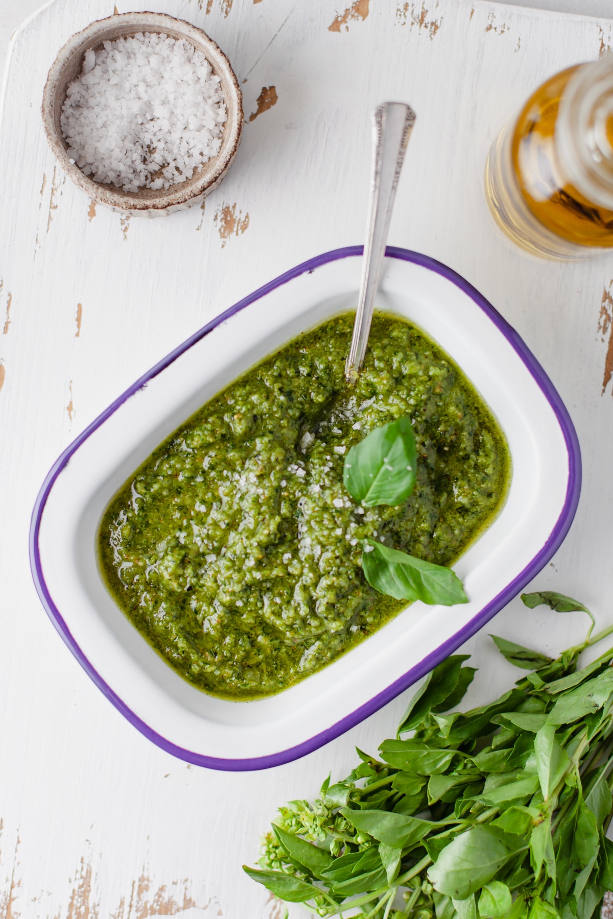 Cashew Pesto in a white serving dish with salt cellar and extra basil bundle