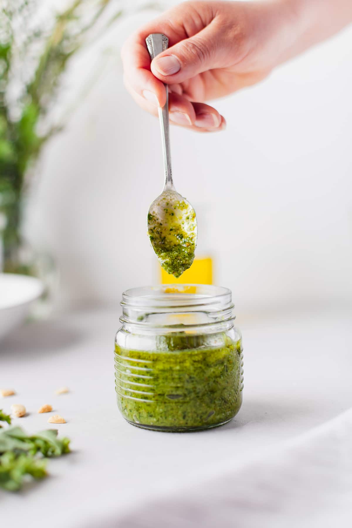 hand with spoon in a glass jar of pesto