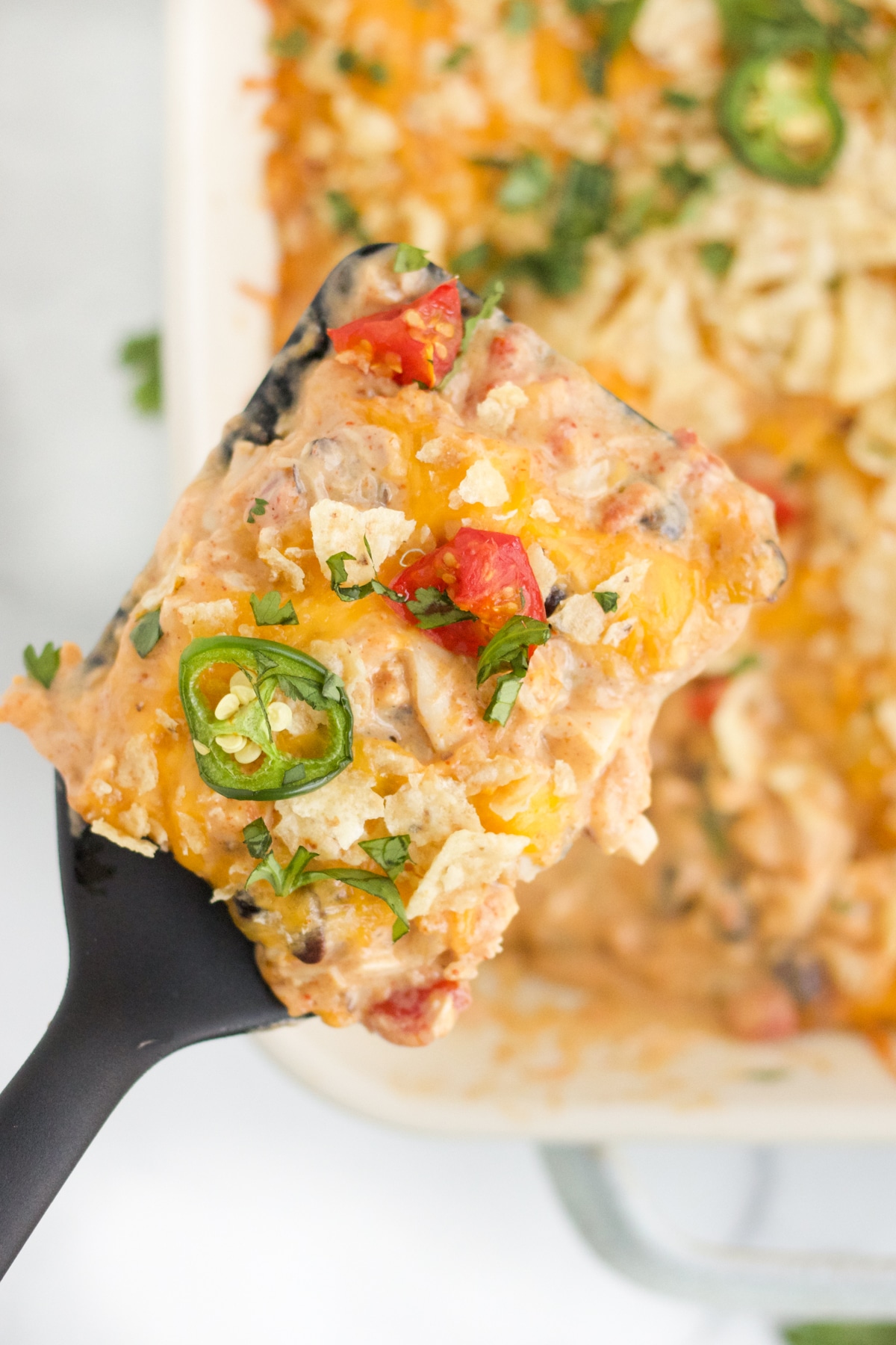 An overhead image of a spatula with a serving of chicken taco casserole on it. 