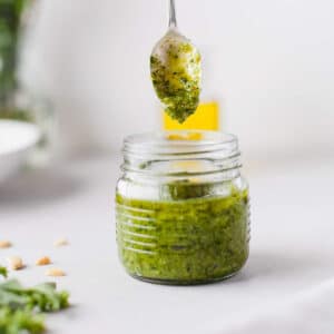 Jar of cashew pesto with a spoon dipping into it.
