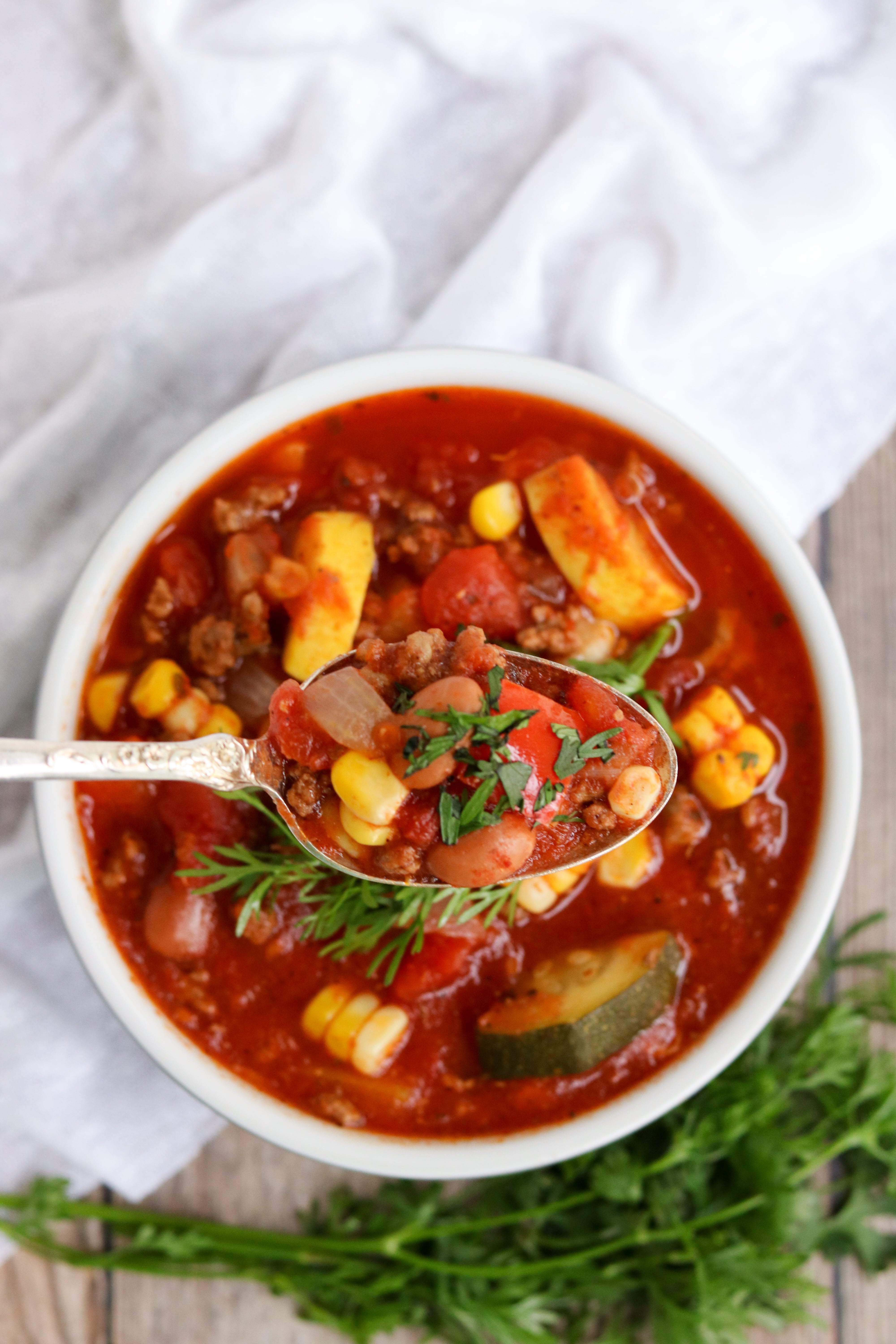 spoonful of summer chili over bowl with cilantro garnish