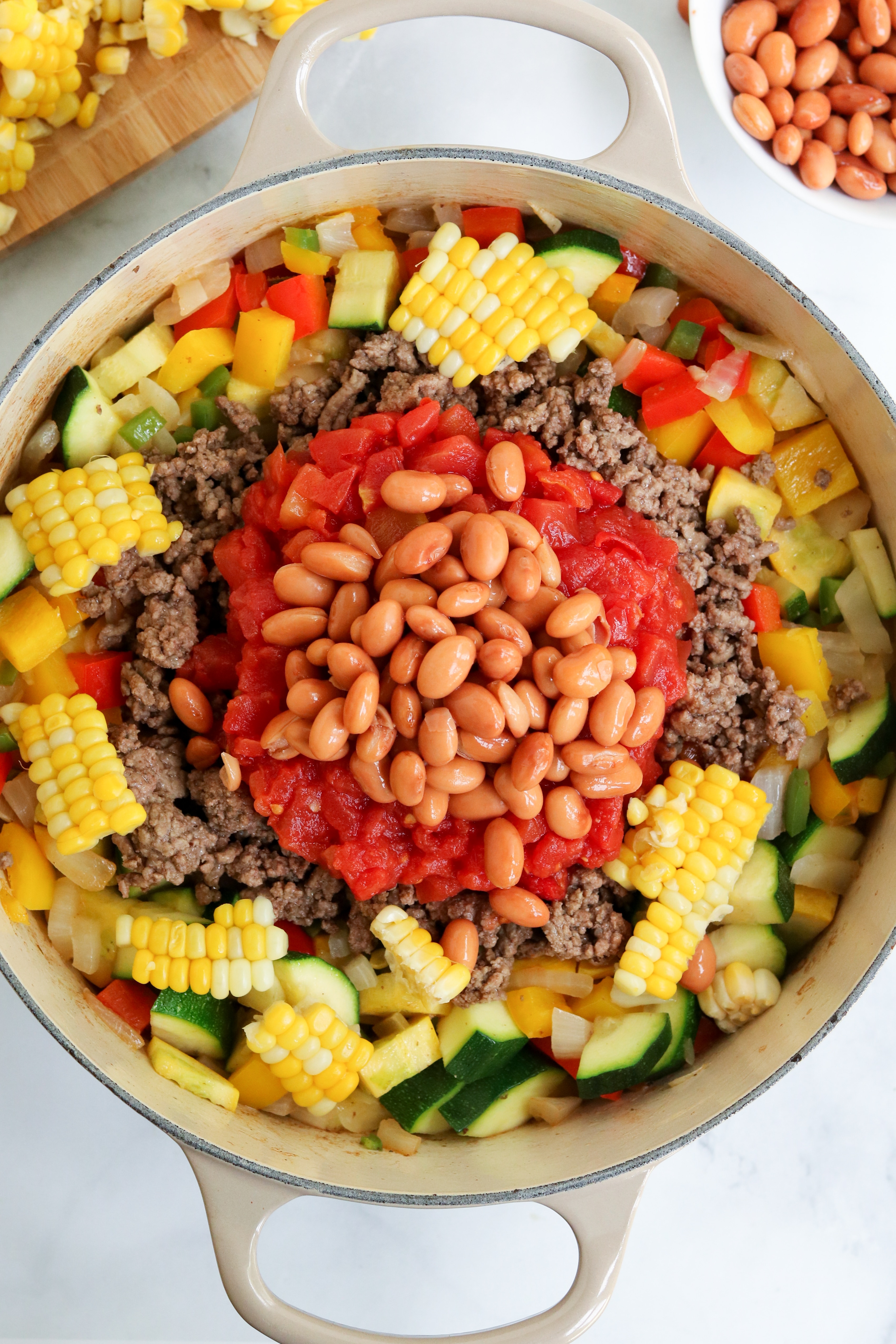 fresh farm veggies, ground beef, tomatoes, and beans in a dutch oven