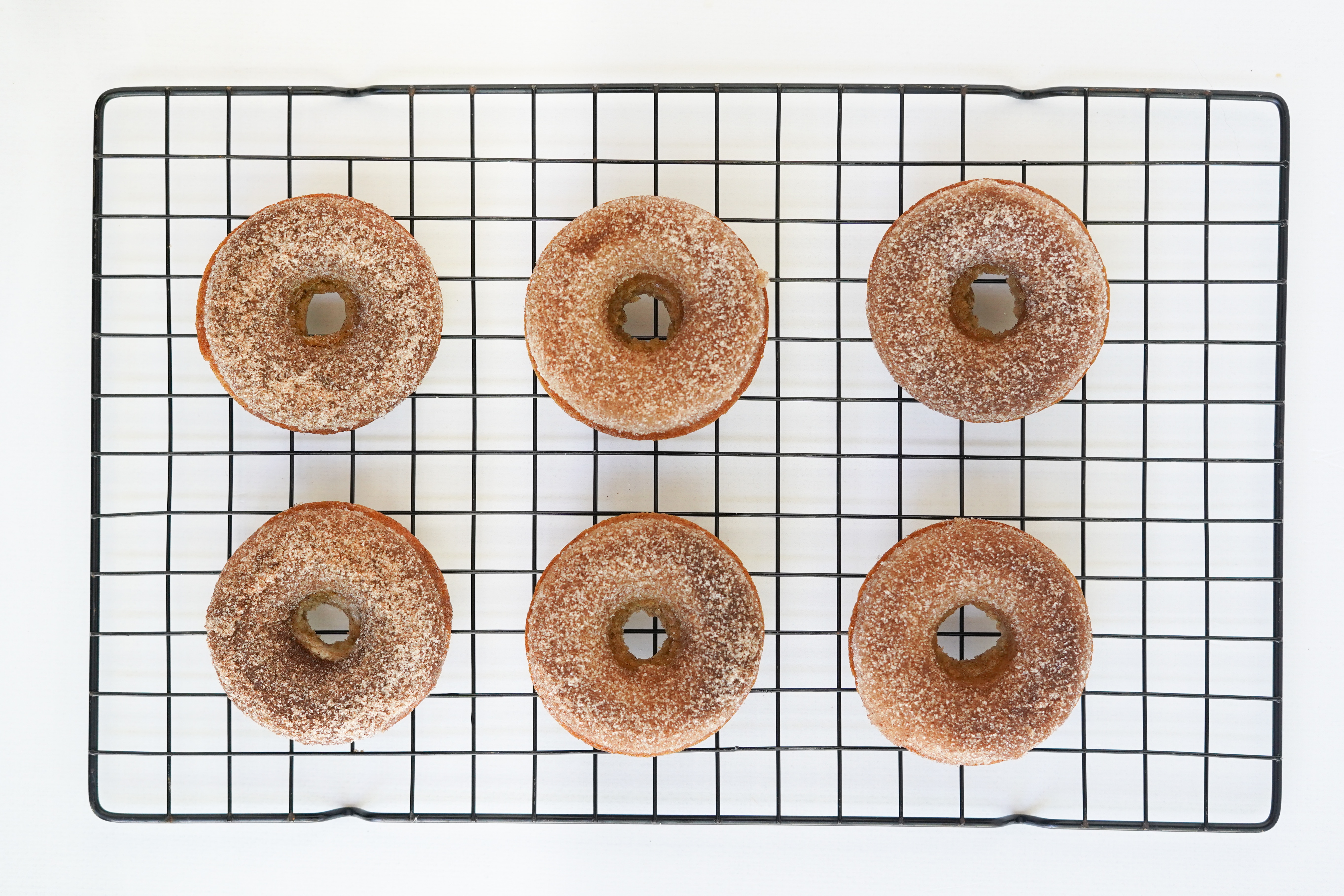 apple cider doughnuts on cooling rack sprinkled with cinnamon and sugar