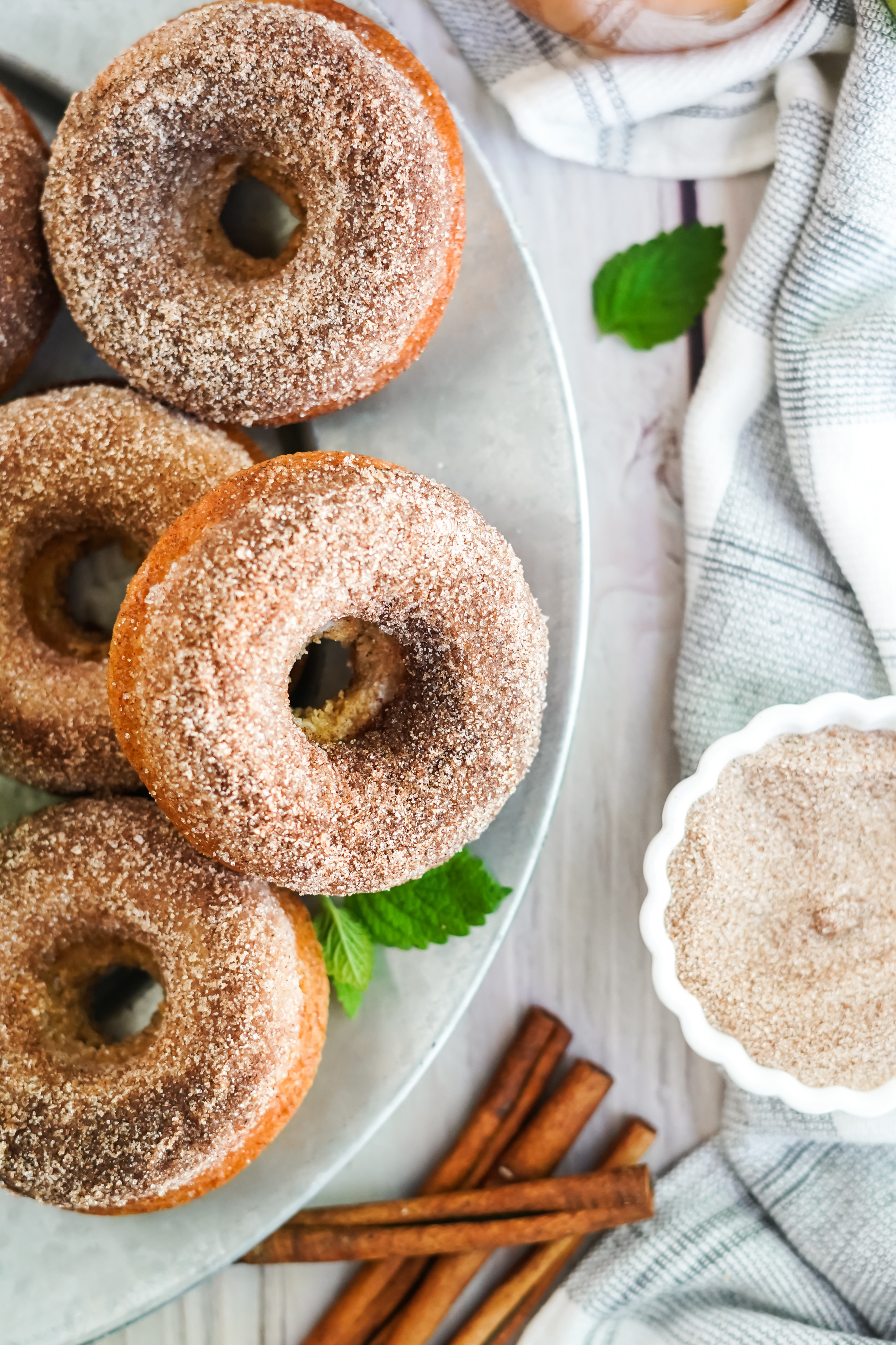 plate of apple cider doughnuts with bowl of cinnamon and sugar