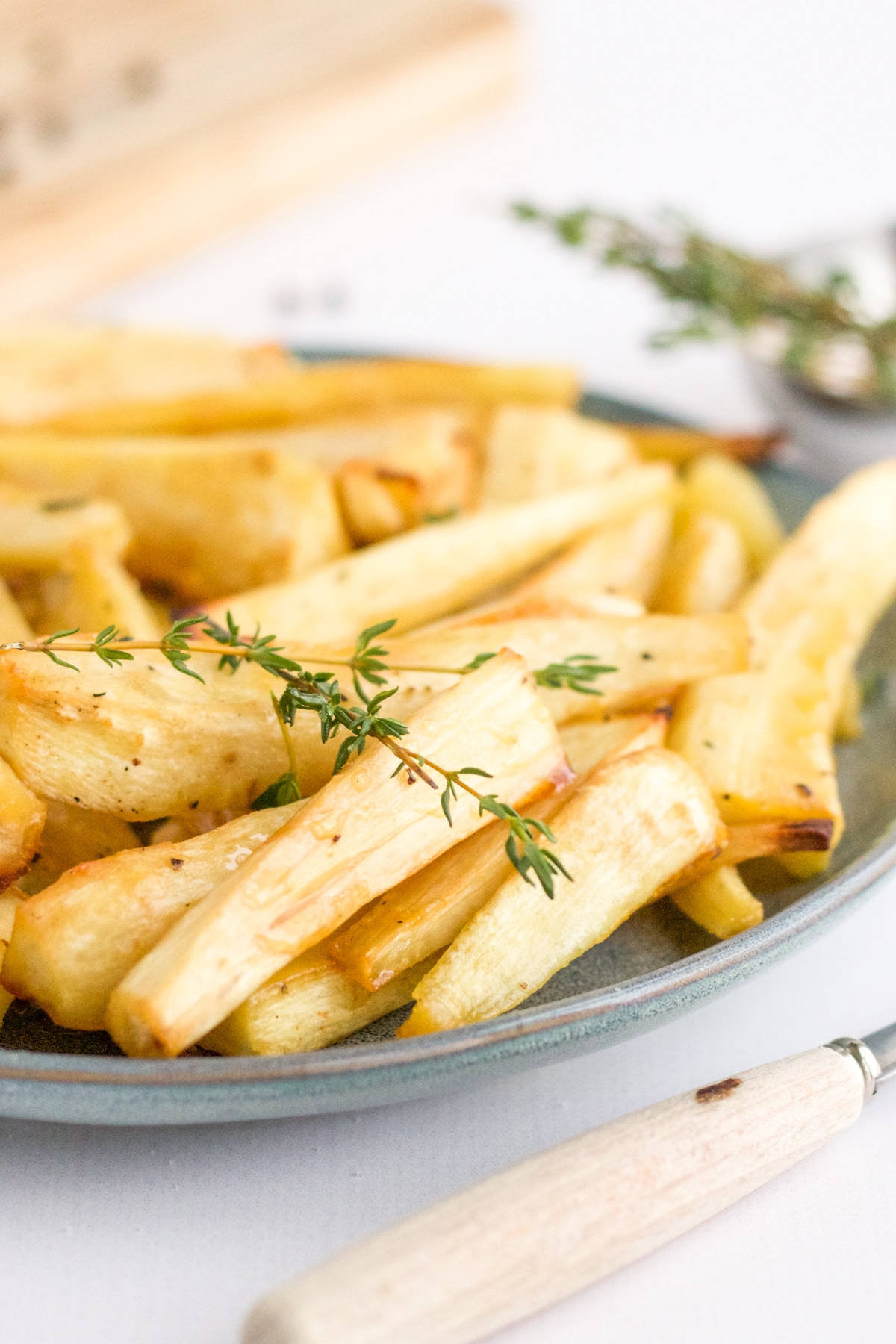 plate of roasted parsnips with fork and thyme garnish