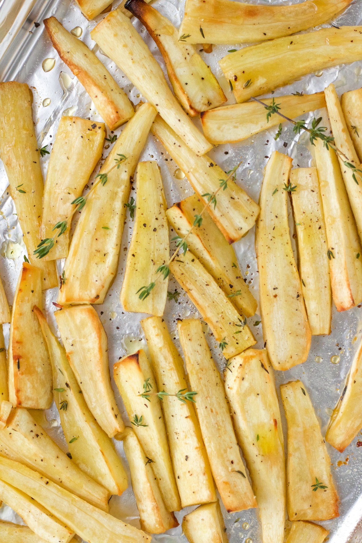 quarter parsnips roasted on a baking sheet with thyme