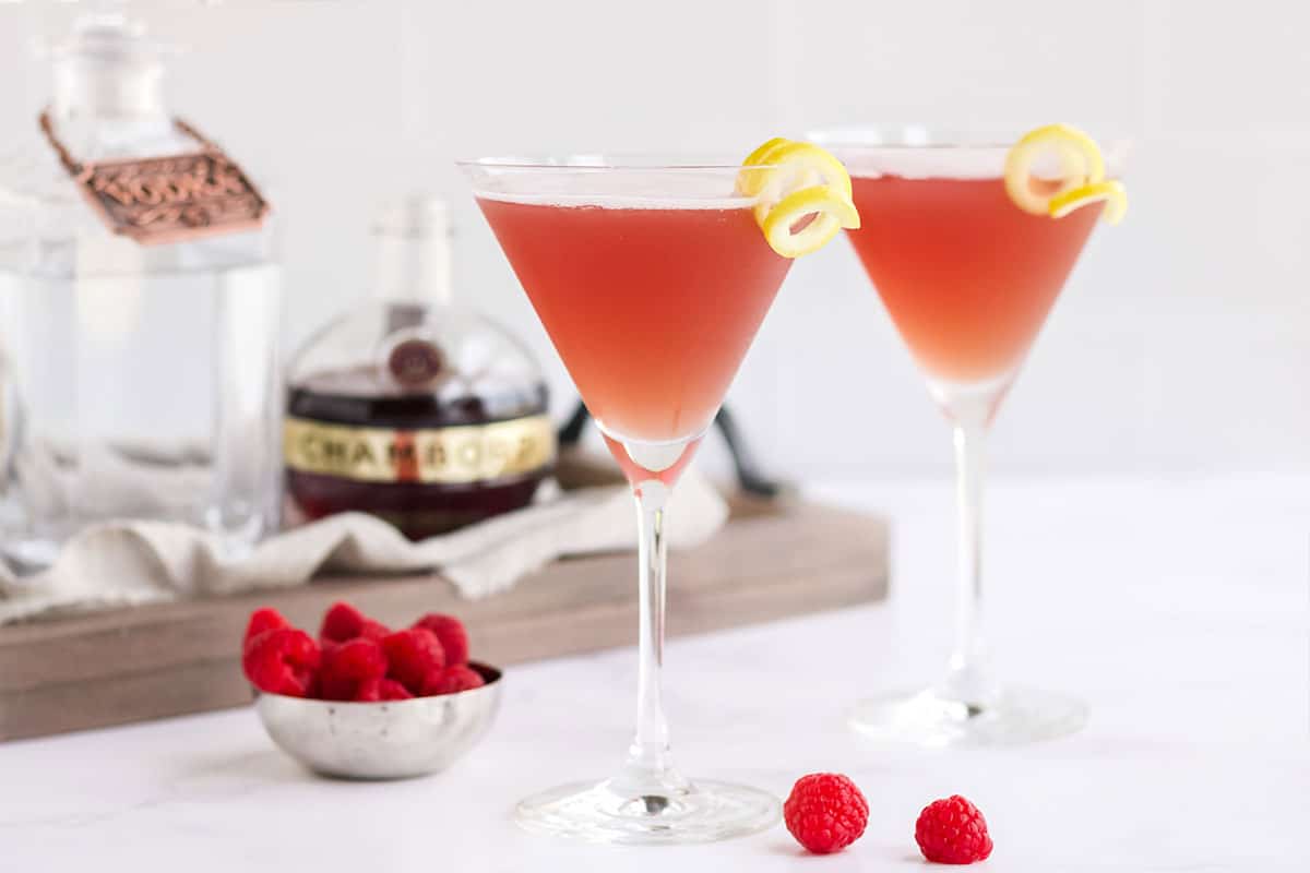 Two glasses of french martini on the table with the ingredients behind it.