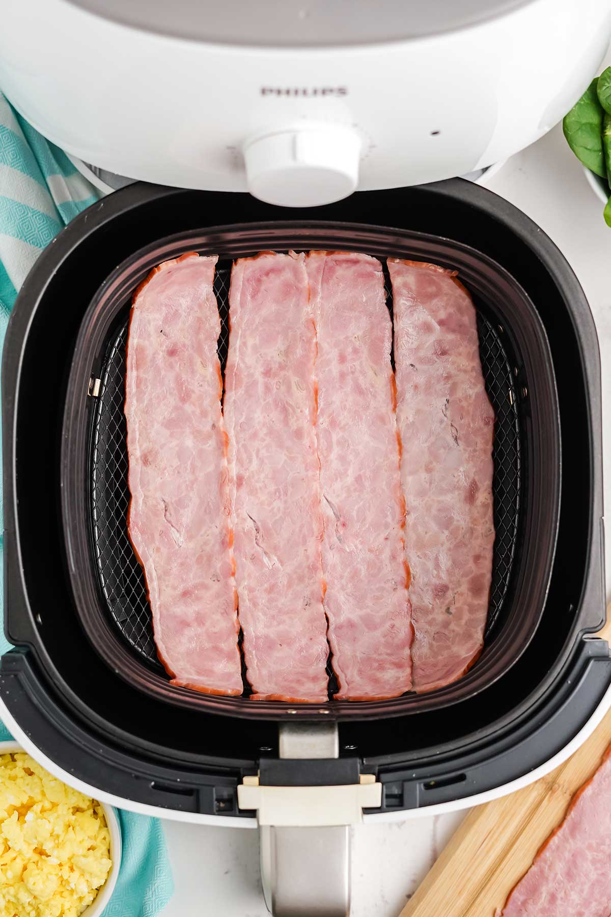 Adding the turkey bacon to the air fryer to cook.