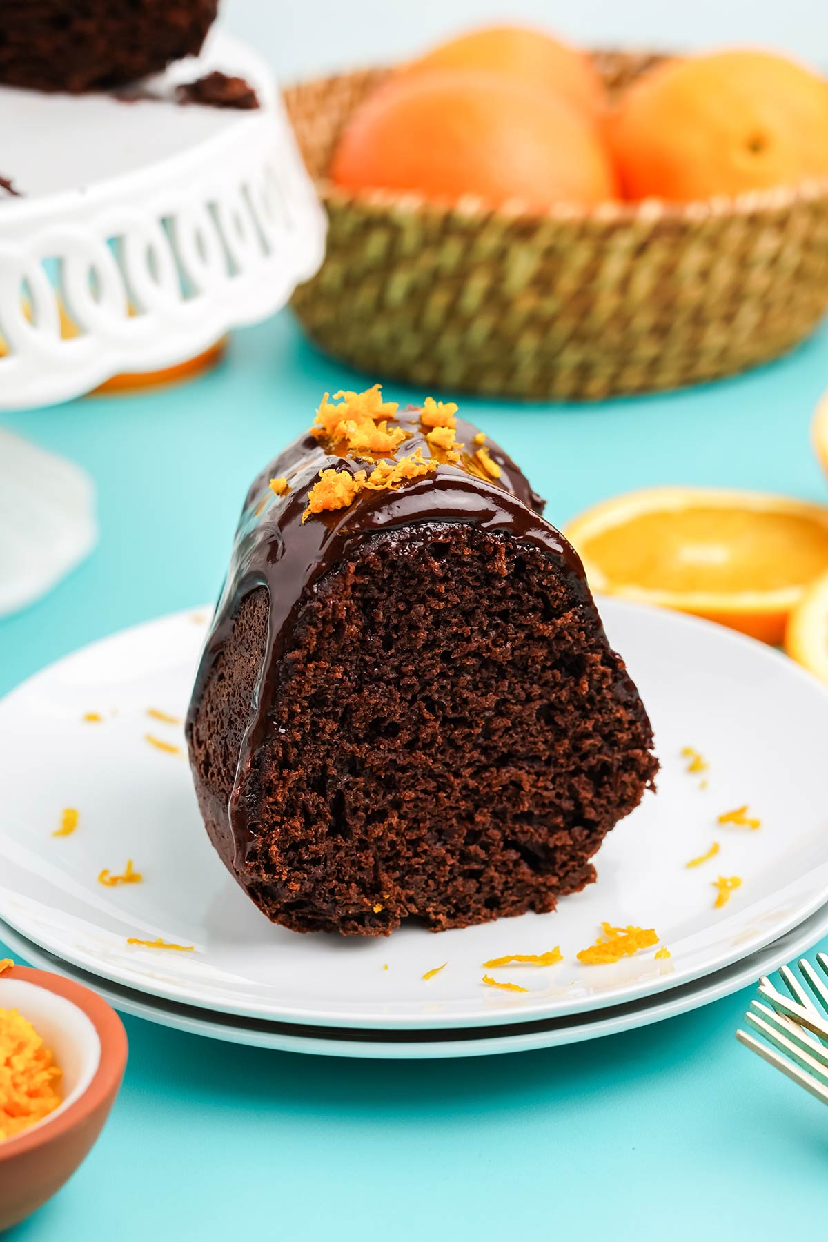 Slice of chocolate and orange cake with ganache on a plate.