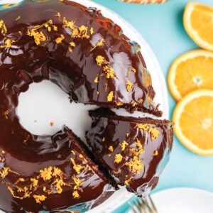 Chocolate orange bundt cake on the table with a piece cut and being served.