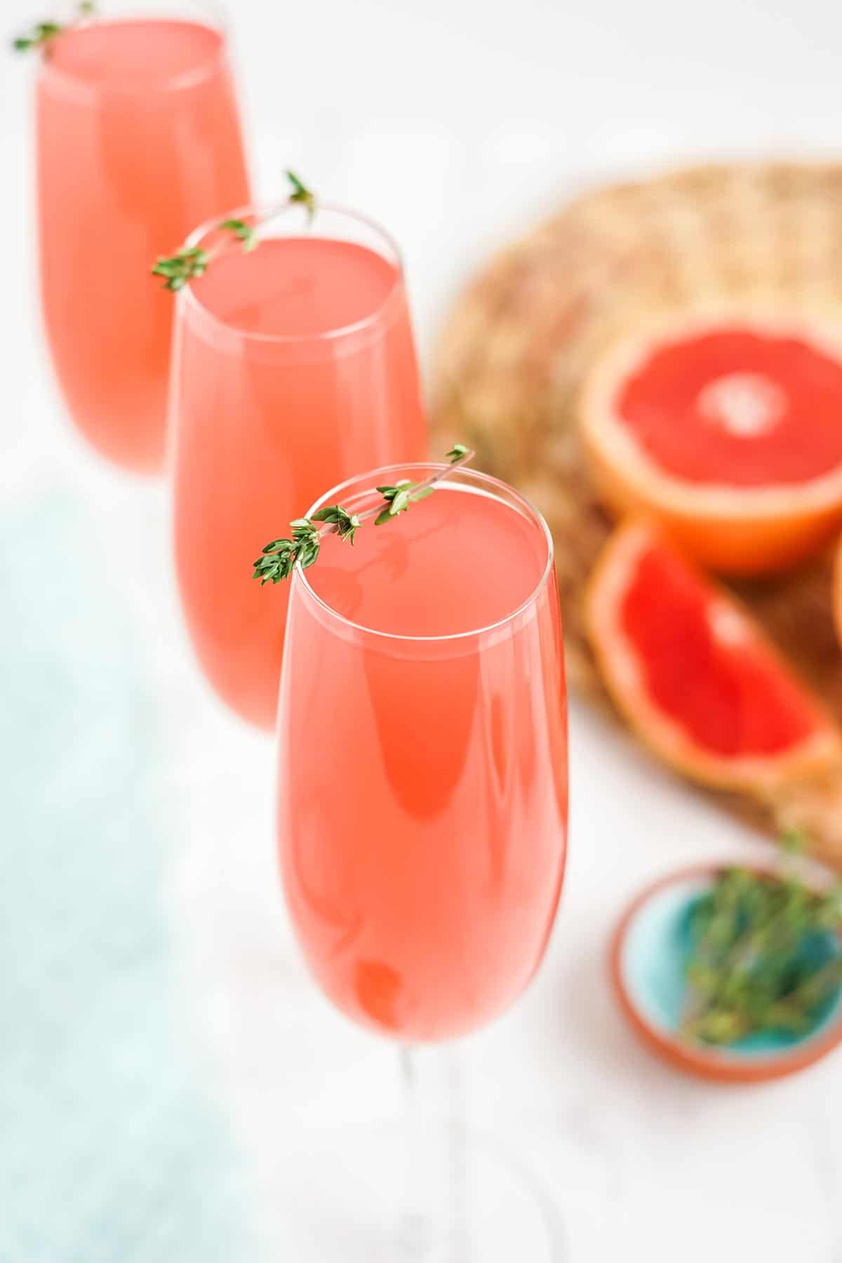 Three glasses of pink grapefruit mimosa on the table in a diagonal.