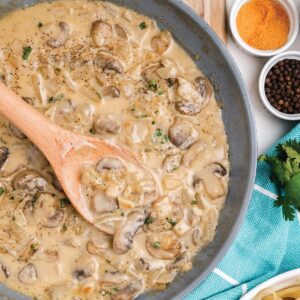 Skillet of white wine mushroom sauce with cream on the table with ingredients and other foods for a meal.