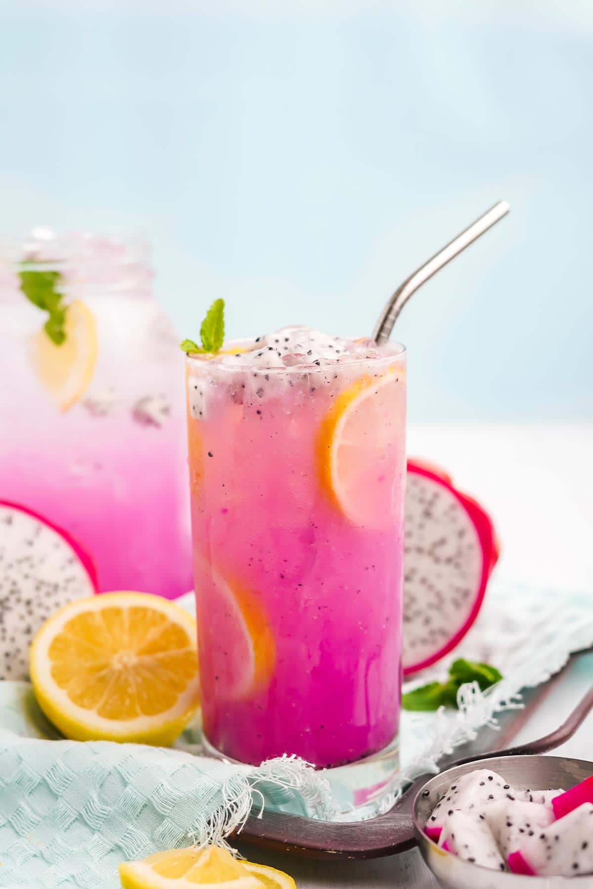 Glass of dragon fruit lemonade with mason jar behind it.