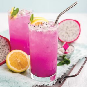 Dragon fruit lemonade in a glass with fresh lemon and a metal straw.