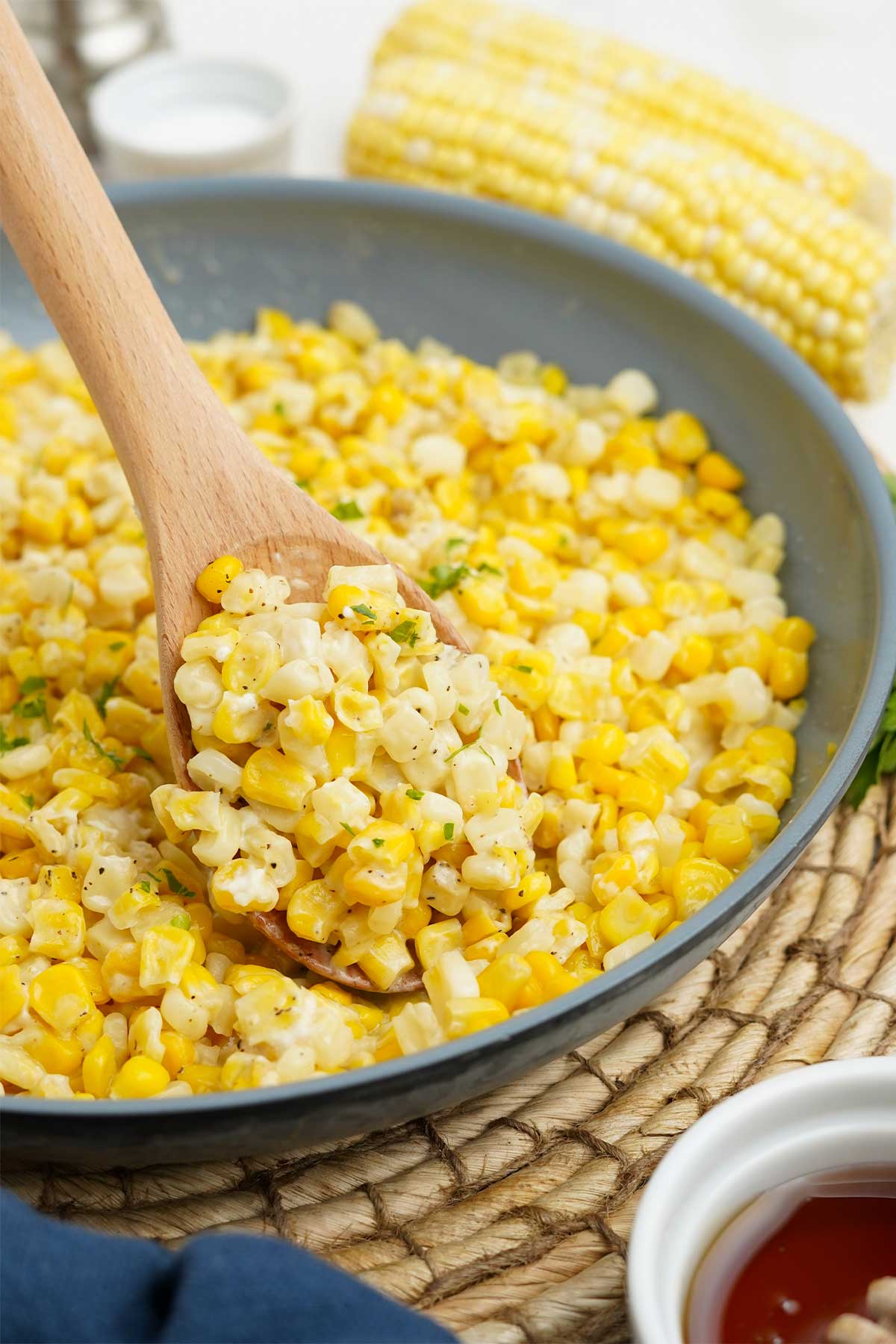 Wooden spoon picking up a spoonful of honey butter skillet corn.