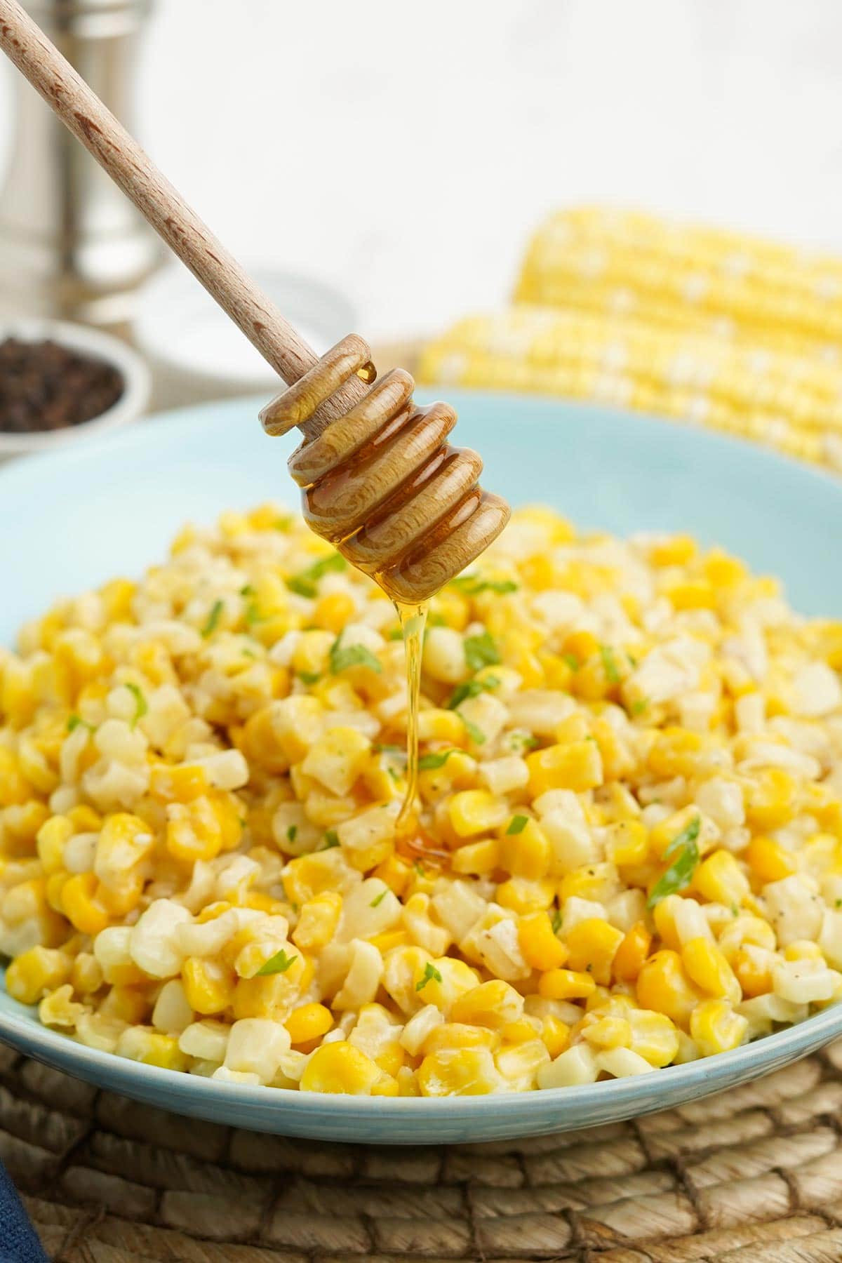 Drizzling some honey over honey butter skillet corn in a bowl.