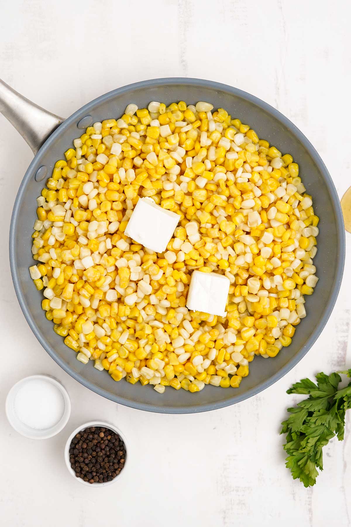 Corn in a skillet with two pats of butter.