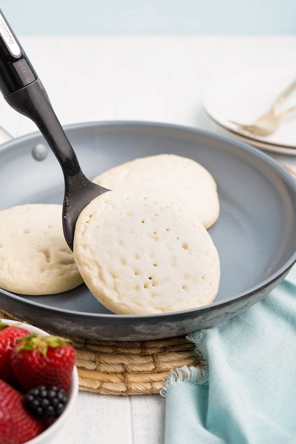 Spatula flipping over an oat milk pancake in the pan.