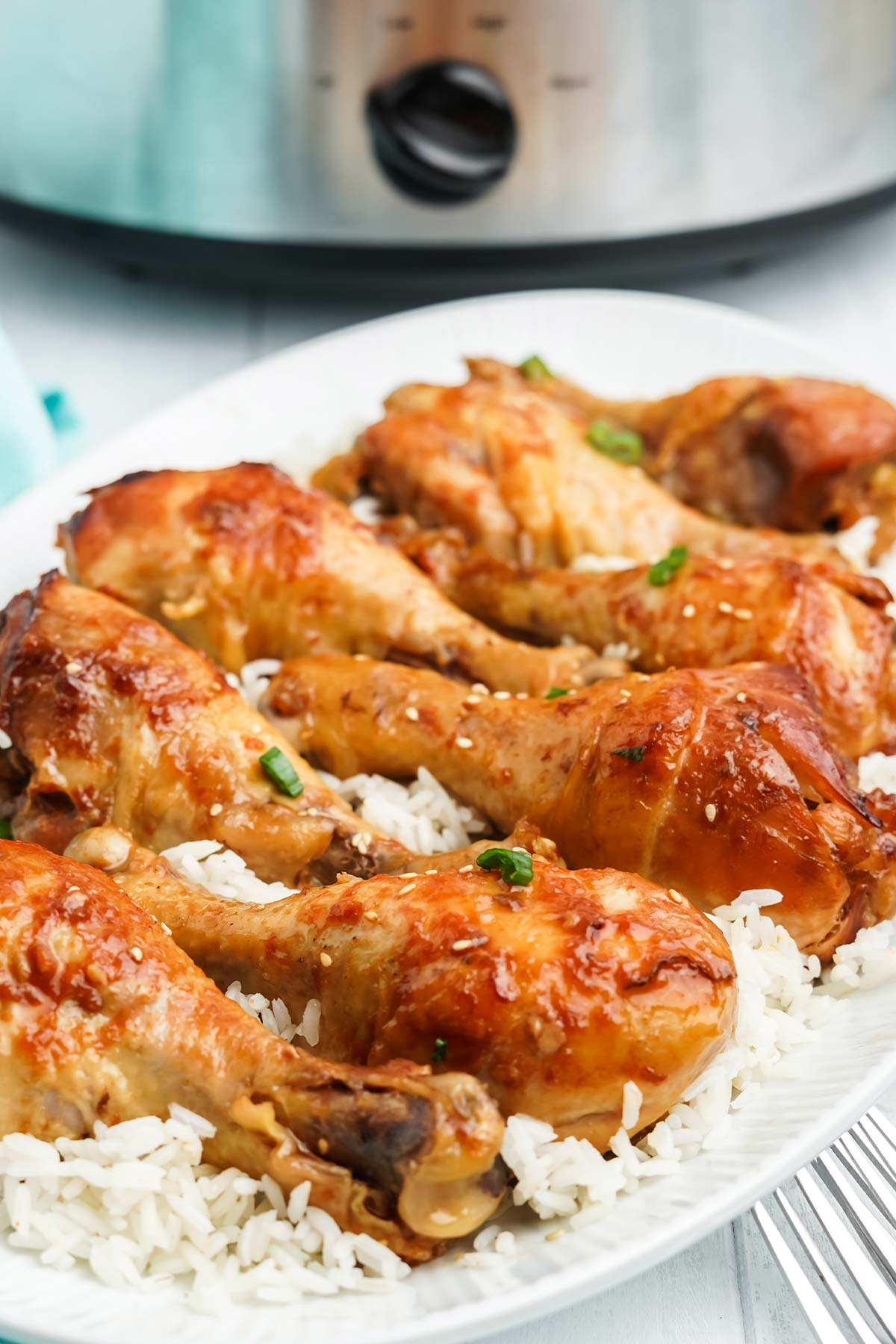 Slow cooker chicken drumsticks served on a platter over a bed of rice.