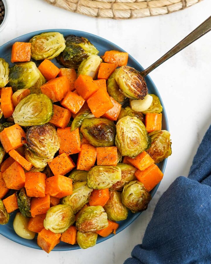 Bowl of brussel sprouts and sweet potatoes with a fork.