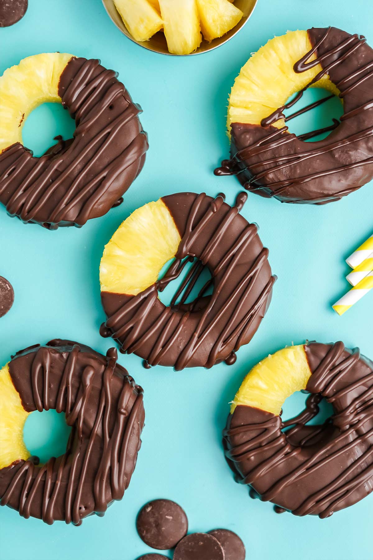 Chocolate covered pineapple on a teal colored background.