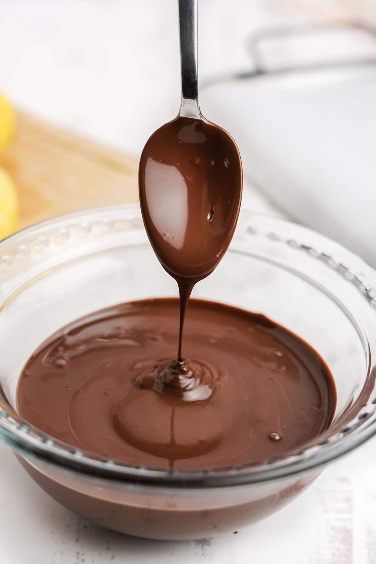 Spoon coming out of bowl of melted chocolate.