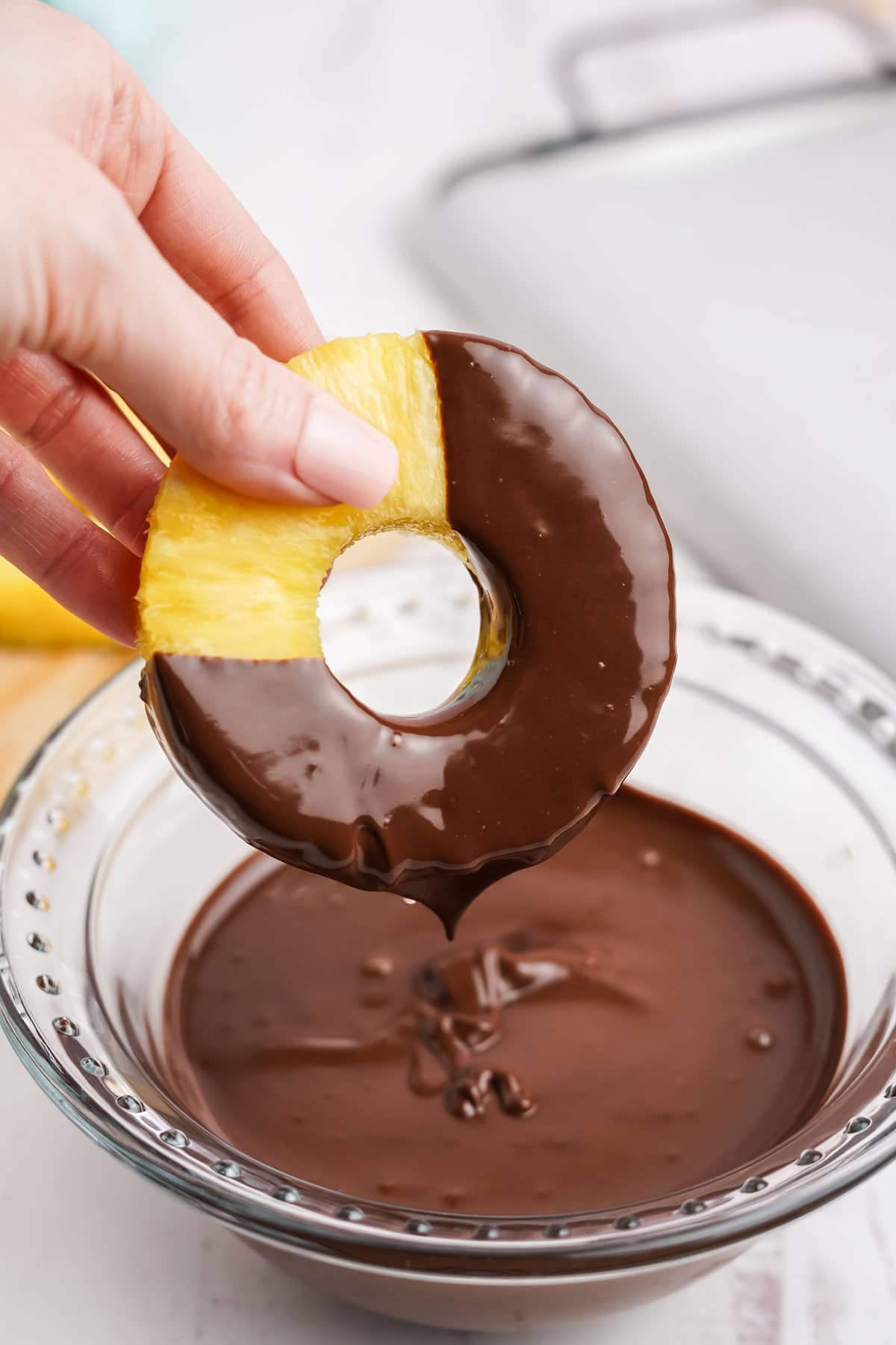 Dipping the pineapple rings into chocolate.