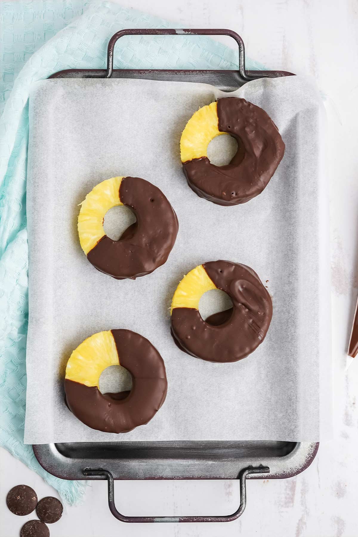 Chocolate dipped pineapple on parchment paper.