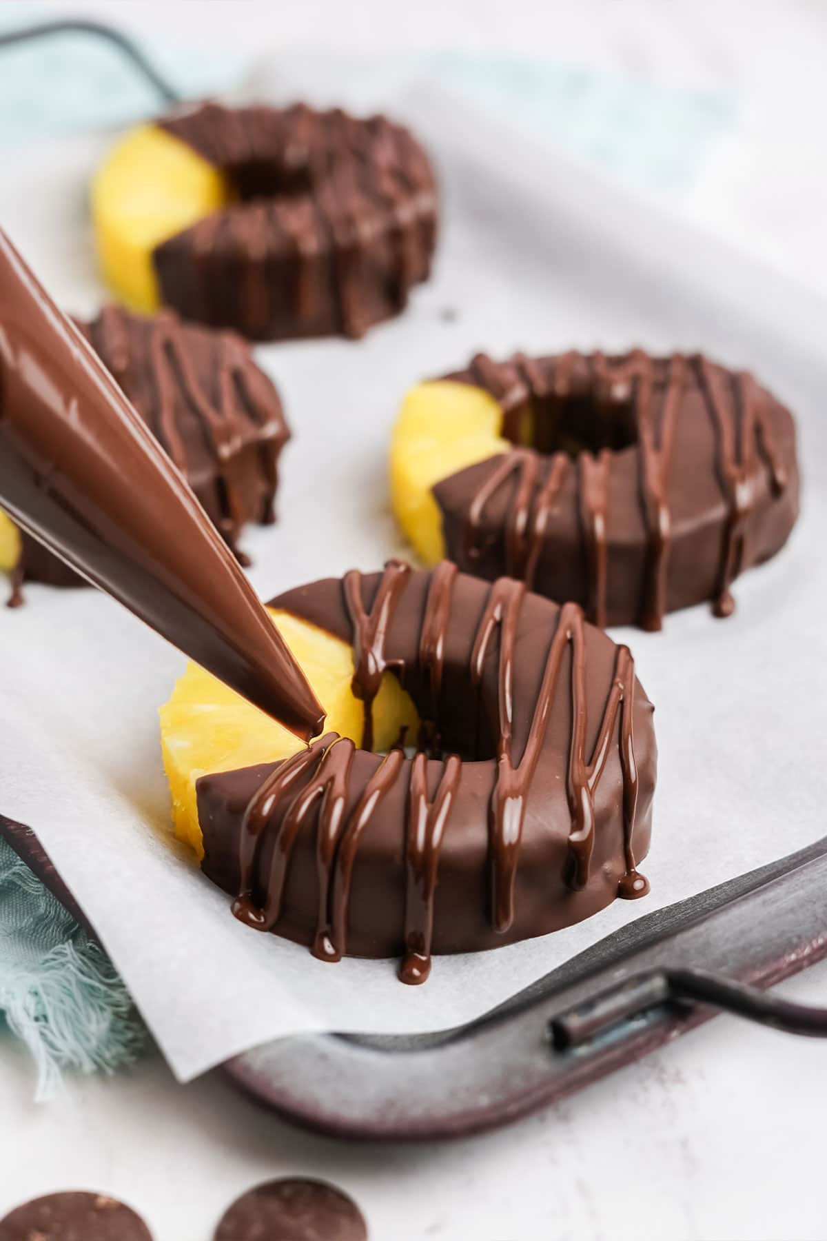 Piping the chocolate strips onto the chocolate covered pineapple rings.