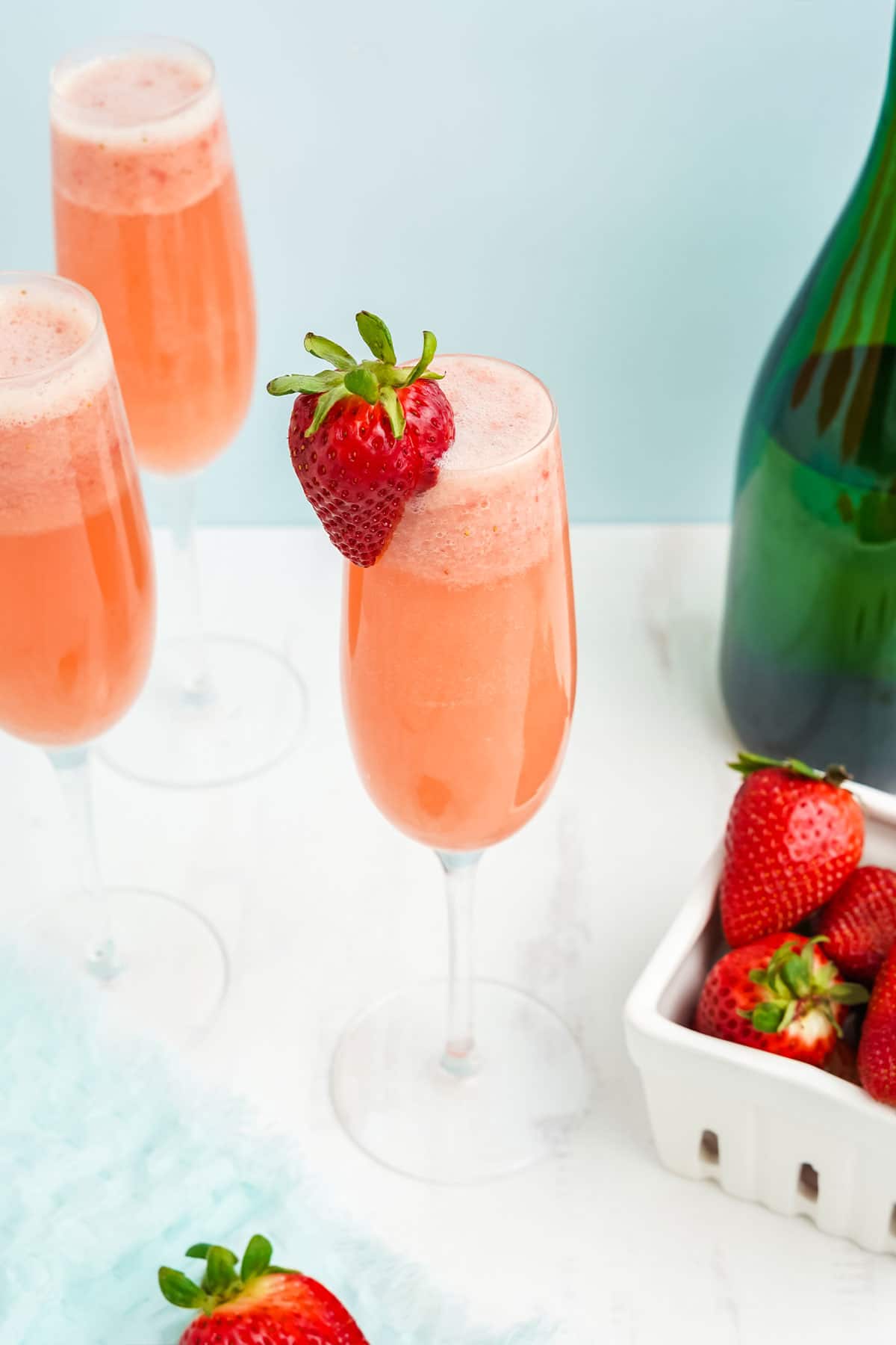Closeup of glass of strawberry mimosa with a strawberry on the rim.