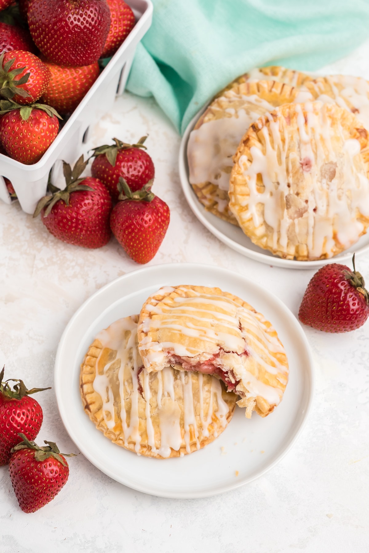 Air fryer strawberry hand pies served up on the table on two plates with fresh strawberries.