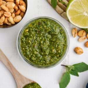 Thai basil pesto in a glass jar with ingredients aroudn it.
