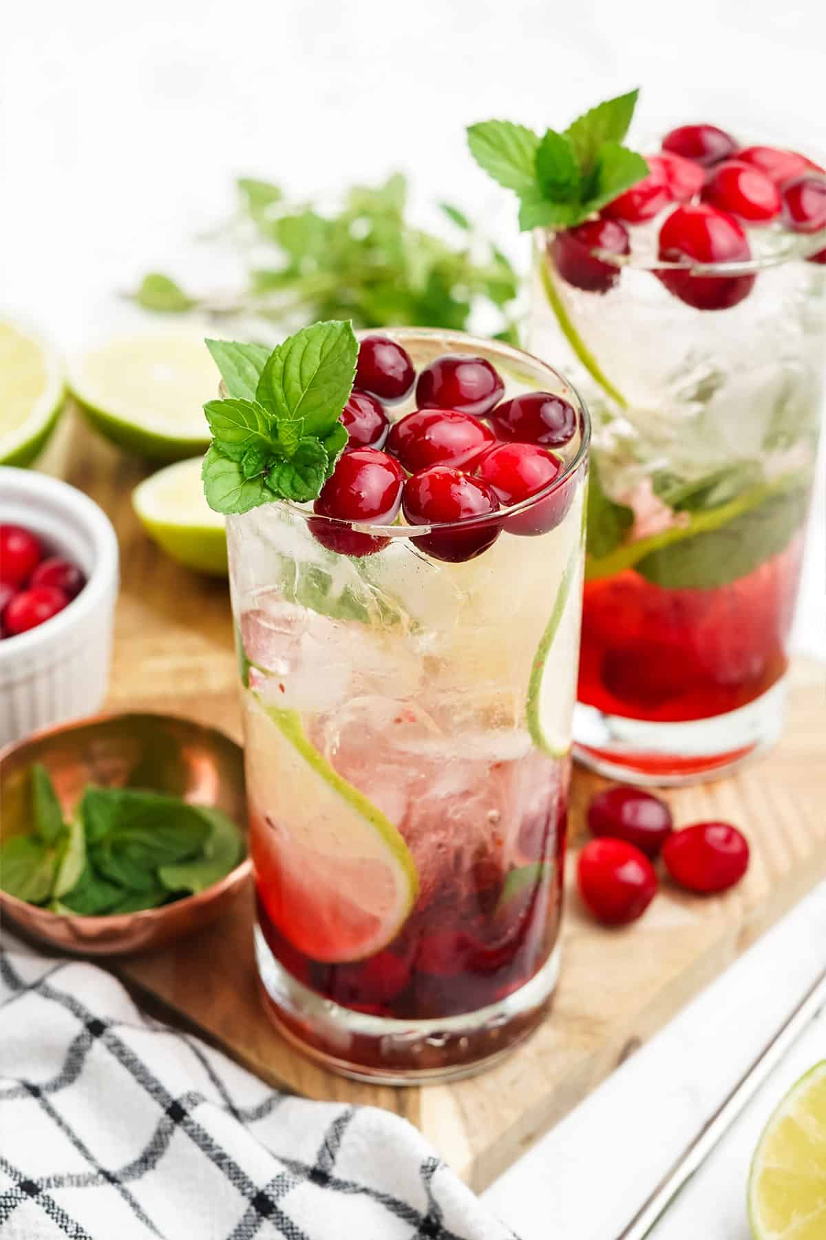 Cranberry mojito in a glass with cranberry syrup on the bottom and lime slices on the glass.