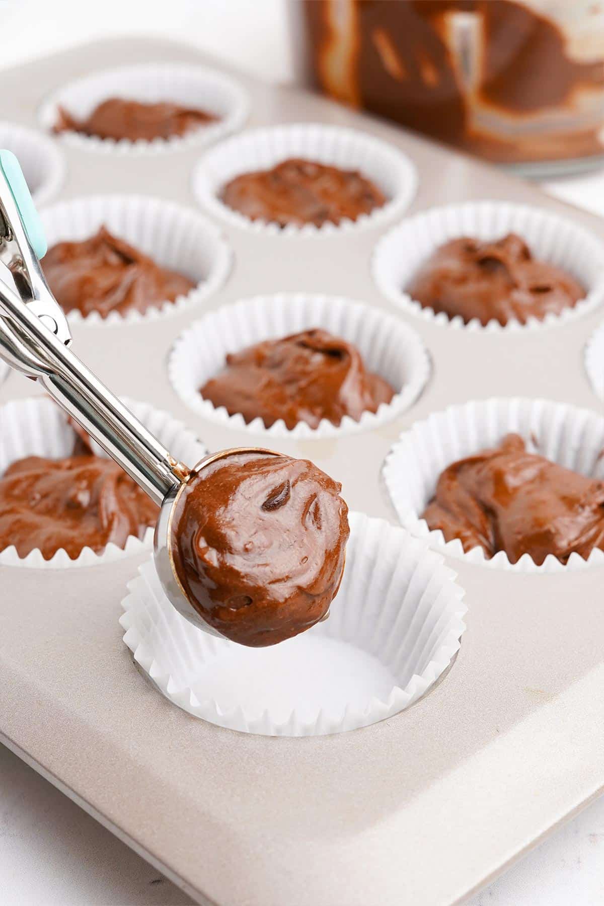 Scooping triple chocolate muffins into paper liners.