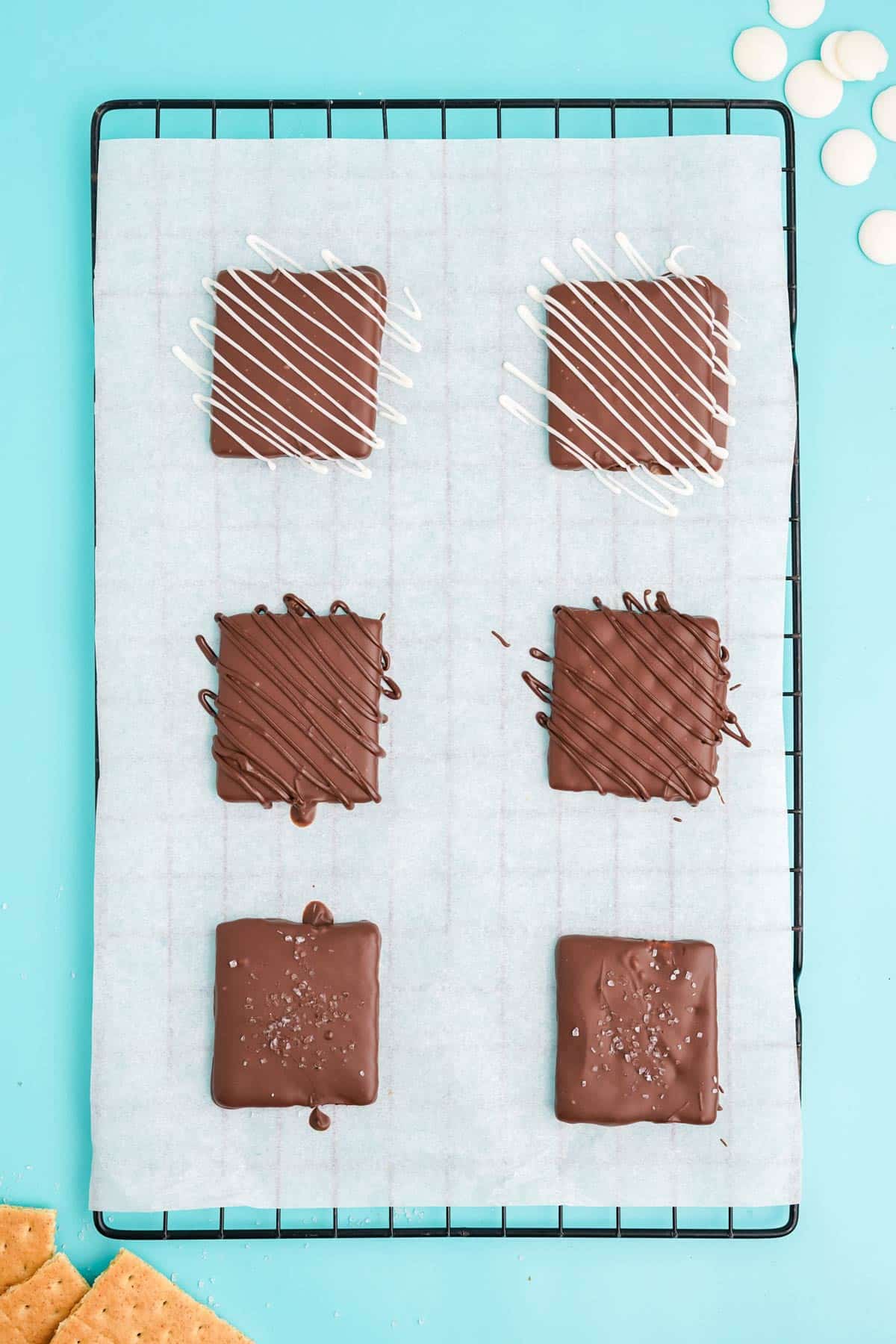 Finished chocolate covered graham crackers with different types of toppings for decoration.