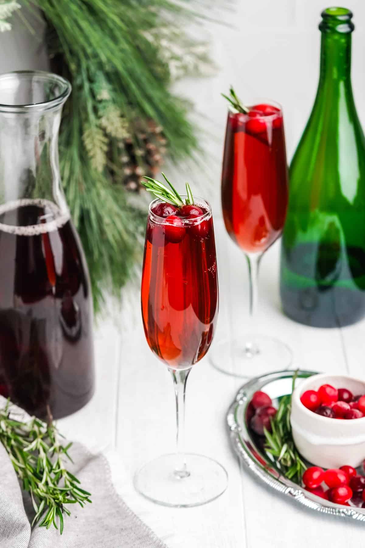Glasses filled with cranberry juice and champagne in glasses with champagne bottle, cranberry juice and fresh cranberries.