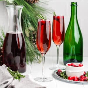 Cranberry mimosas on a holiday table with cranberry juice, champagne and fresh cranberries.