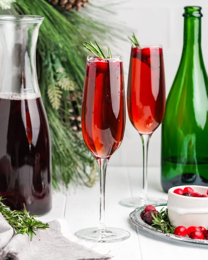 Cranberry mimosas on a holiday table with cranberry juice, champagne and fresh cranberries.