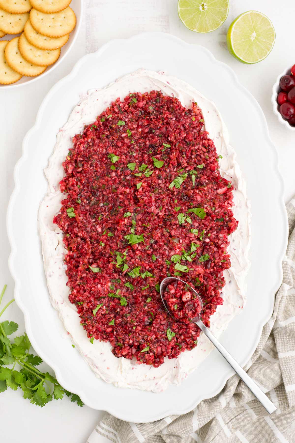 A platter of cranberry jalapeno dip on a white oval platter with a spoon.