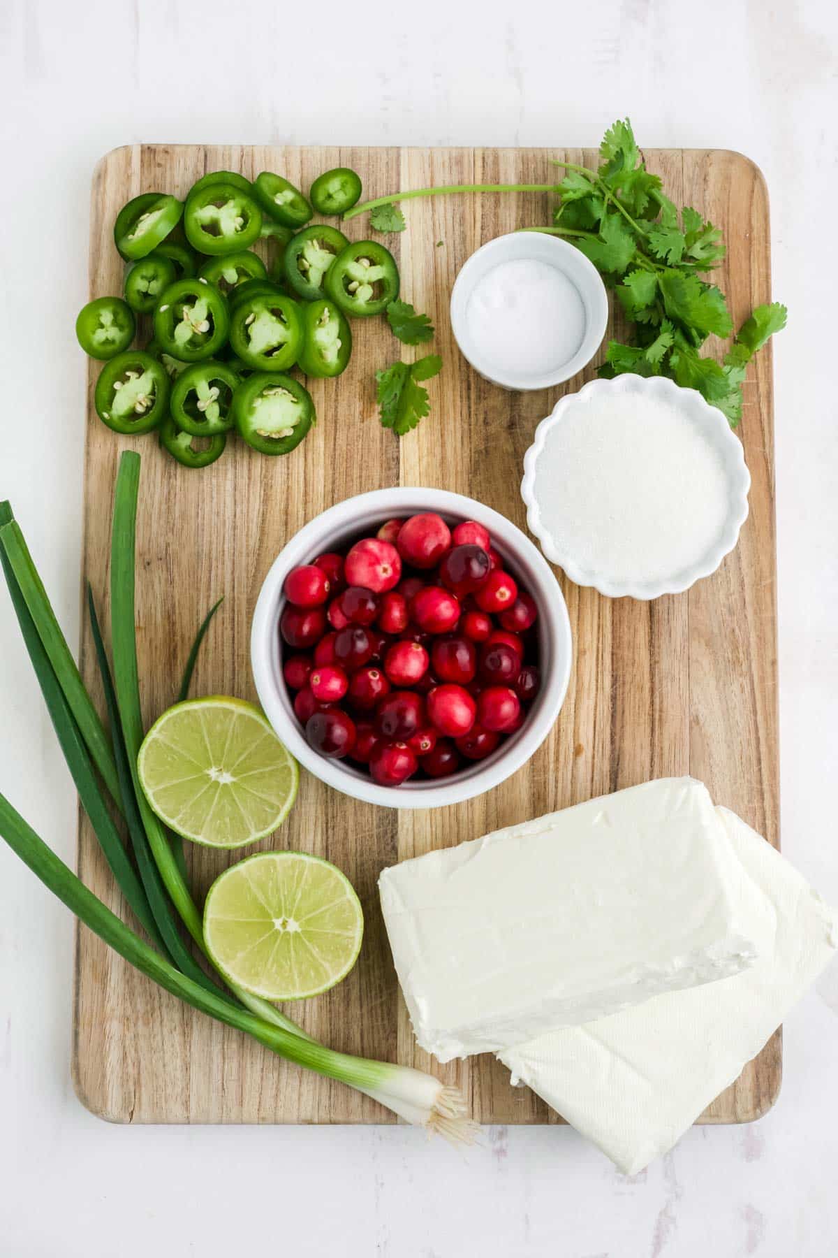 Ingredients to make jalapeno cranberry dip on a cutting board.