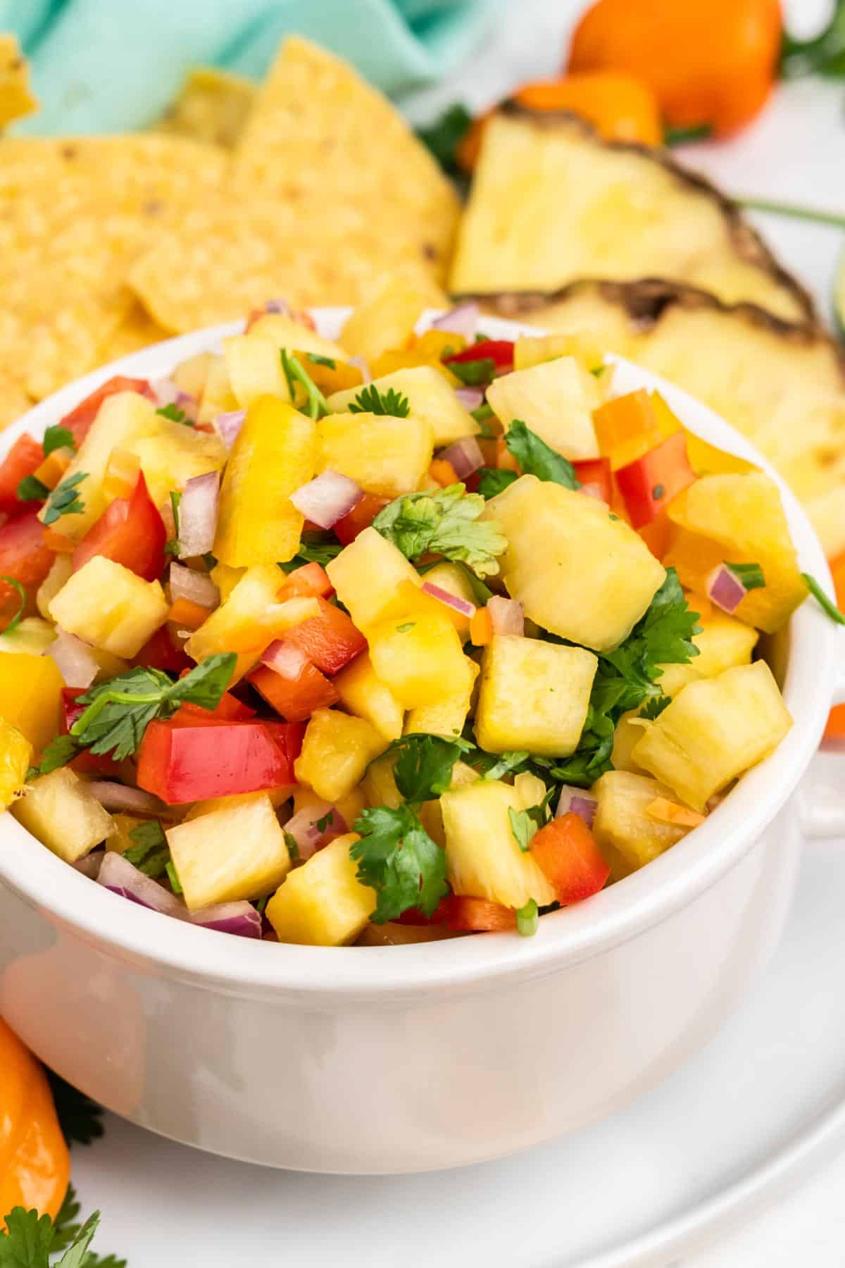 Bowl of pineapple pico de gallo on a plate with chips.