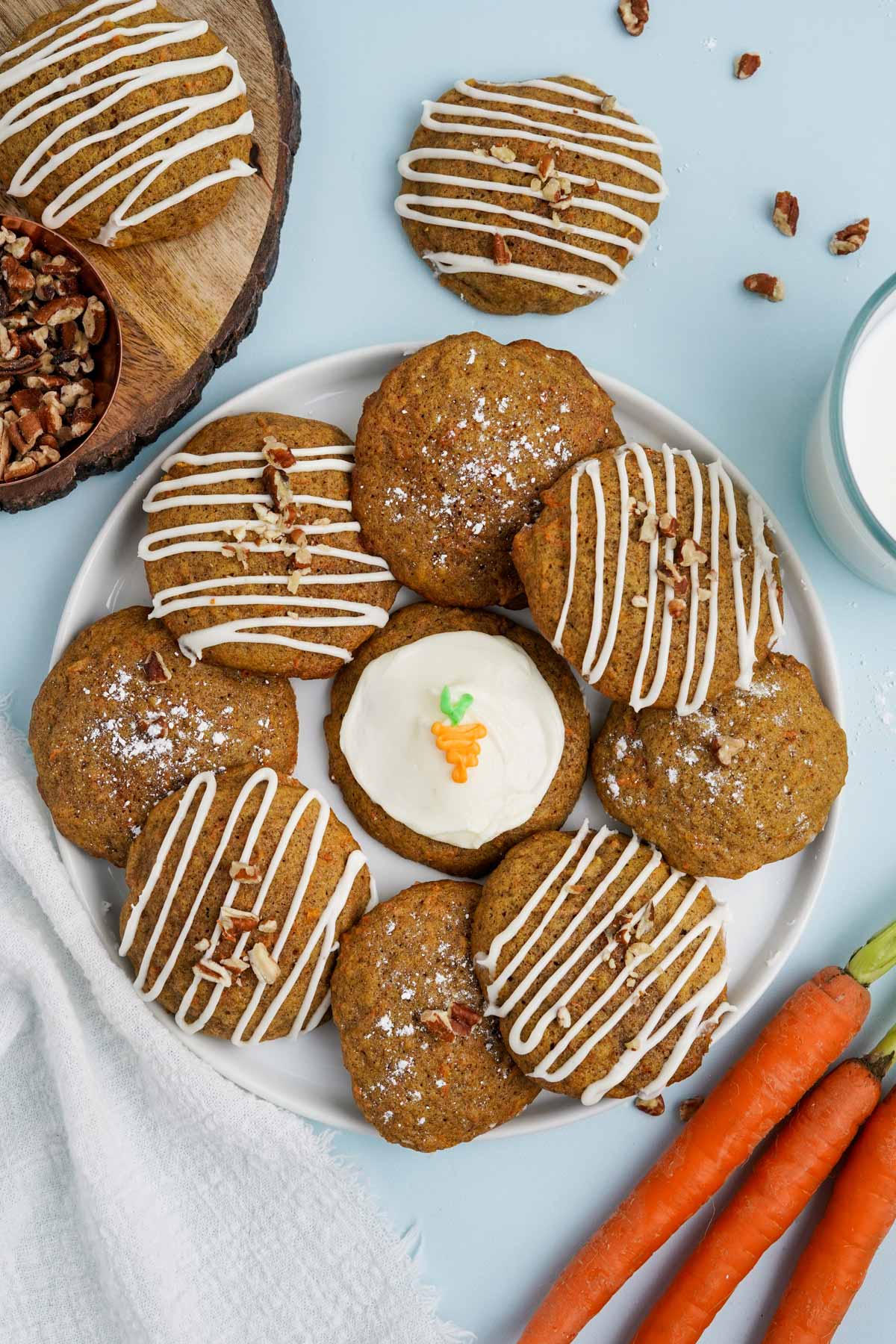 Carrot cake cookies on a plate some with icing on top and others with icing drizzle.