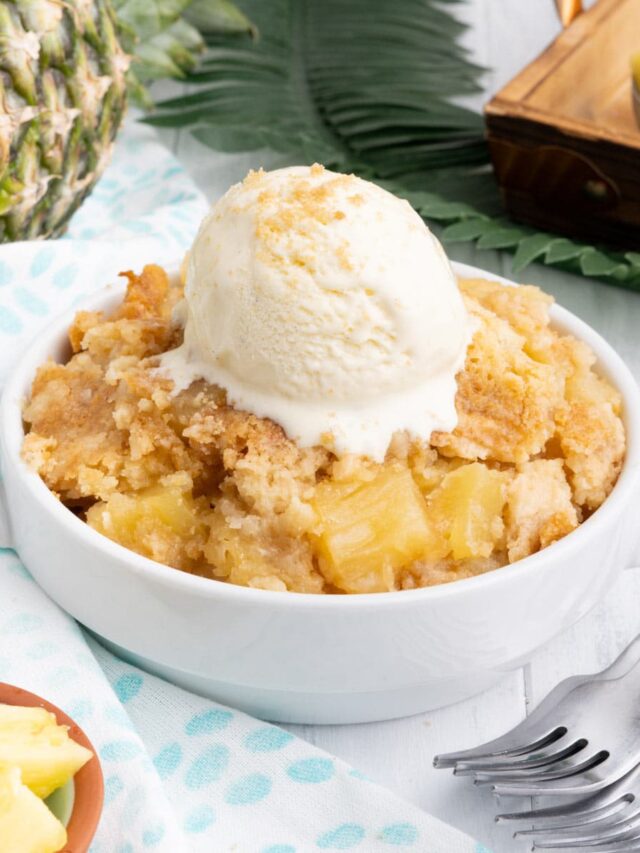 Pineapple dump cake in a white bowl with a scoop of ice cream.