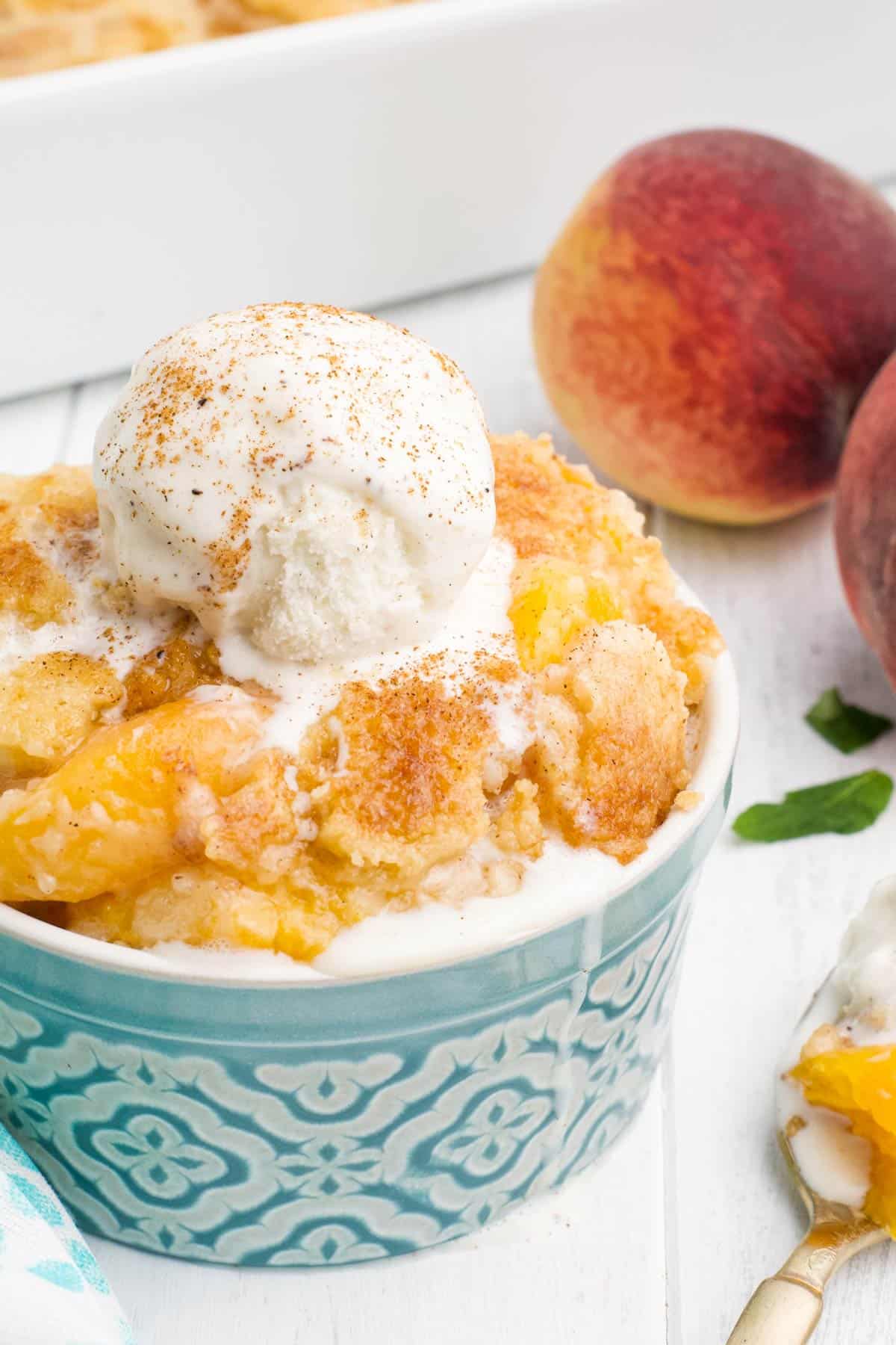 Peach dump cake in a bowl topped with ice cream.