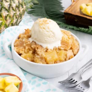 Pineapple dump cake in a white bowl with a scoop of ice cream.